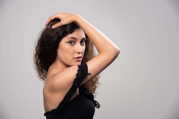 Jovem mulher posando de blusa preta com cabelo encaracolado. Foto de alta qualidade