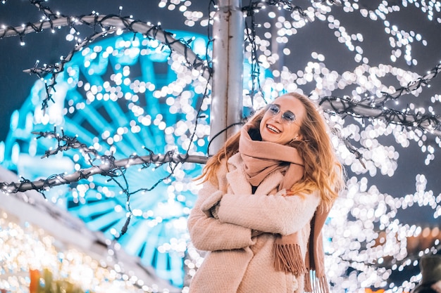 Foto grátis jovem mulher posando na rua com árvores iluminadas