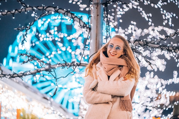 Jovem mulher posando na rua com árvores iluminadas