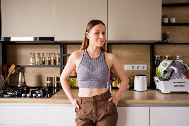 Jovem mulher posando no fundo da cozinha moderna