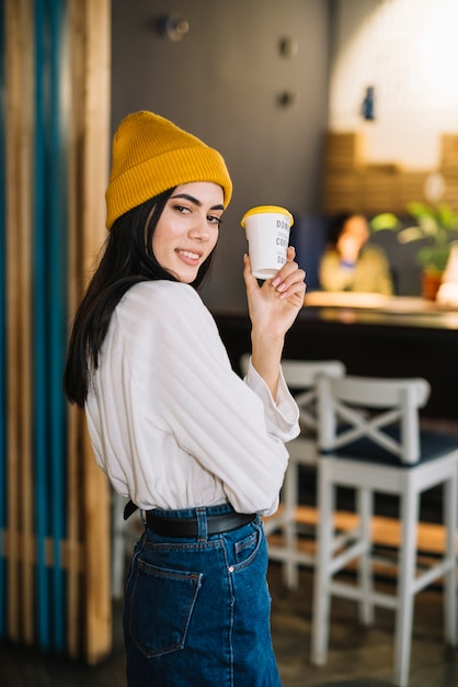 Jovem mulher positiva com copo no café