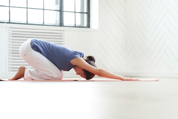 Jovem mulher praticando ioga em um tapete de ioga