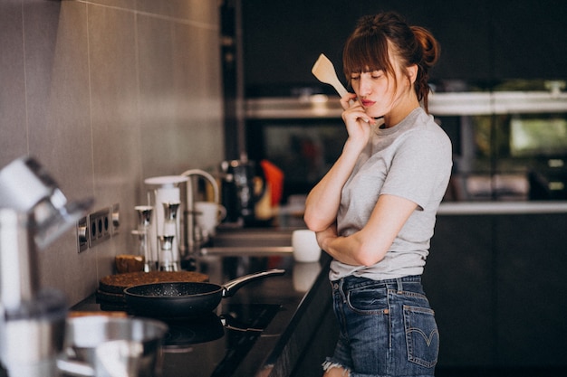 Jovem mulher preparando o café da manhã na cozinha pela manhã