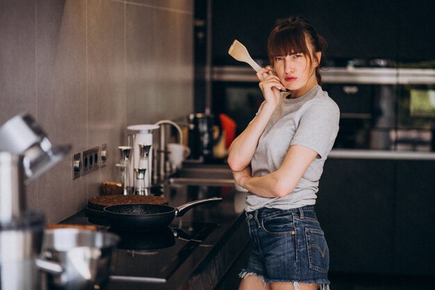 Jovem mulher preparando o café da manhã na cozinha pela manhã