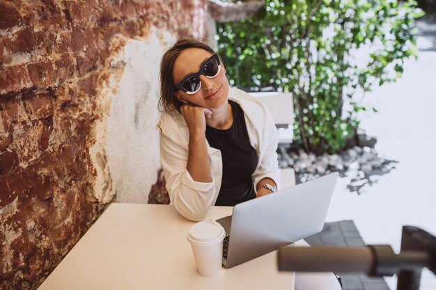 Jovem mulher que trabalha no laptop em um café