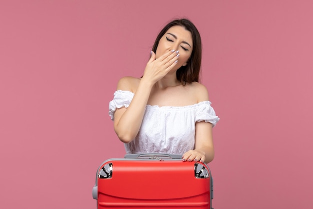 Jovem mulher se preparando para as férias com sua bolsa grande bocejando sobre fundo rosa no exterior