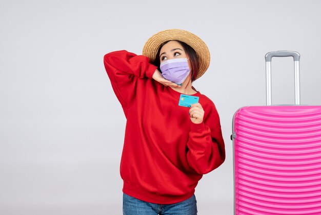 Jovem mulher se preparando para uma viagem com máscara na parede branca