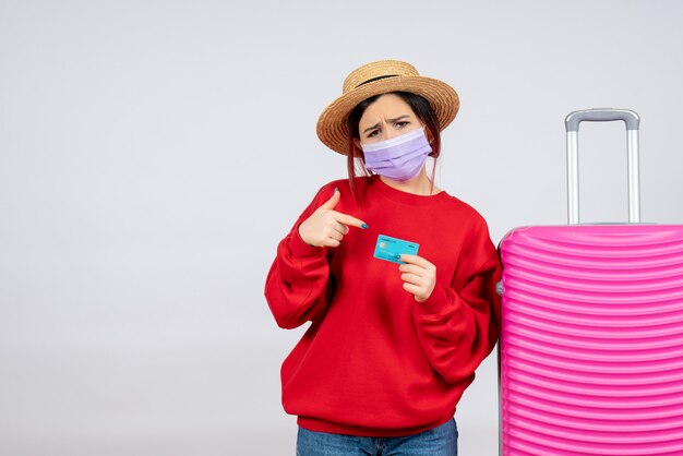 Jovem mulher se preparando para uma viagem com máscara na parede branca