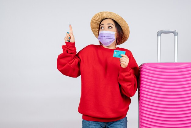 Jovem mulher se preparando para uma viagem com máscara na parede branca