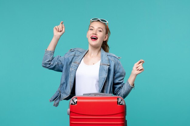 Jovem mulher se preparando para uma viagem e dançando no espaço azul