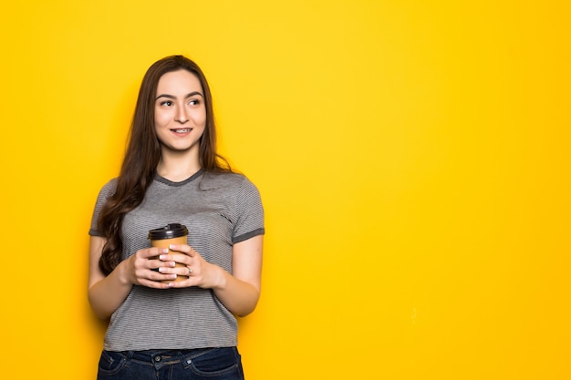 Jovem mulher segurando a xícara com chá ou café na parede amarela. Conceito de estilo de vida e comida. Fechar-se.