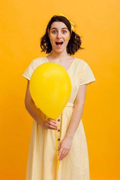 Jovem mulher segurando balão amarelo