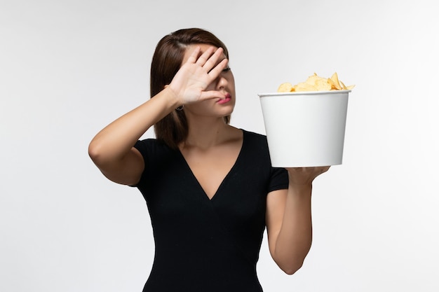 Jovem mulher segurando batatas fritas e assistindo a um filme interessante na superfície branca