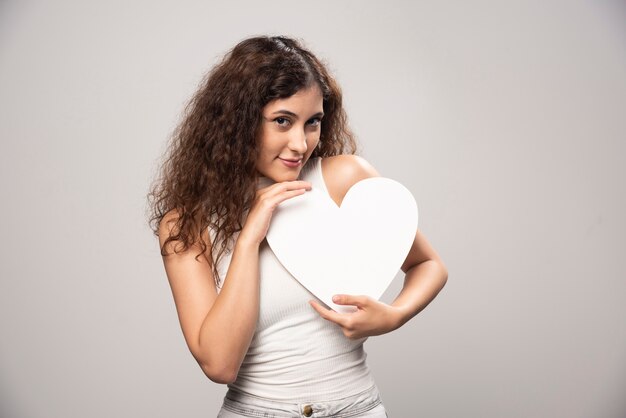 Jovem mulher segurando coração branco de papel artesanal. Foto de alta qualidade