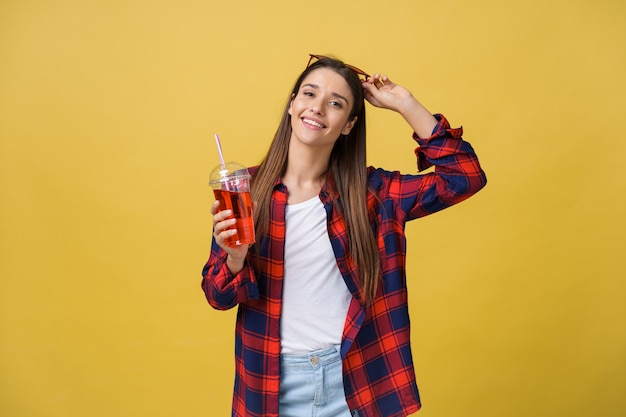 Jovem mulher segurando e bebendo bebida gelada em roupas casuais. menina bonita sorrindo feliz rindo olhando para a câmera.