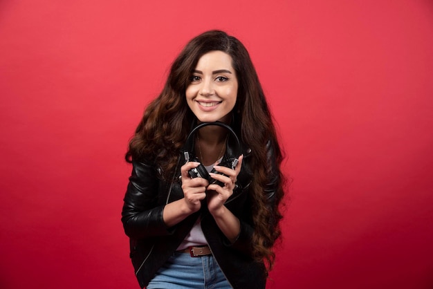 Jovem mulher segurando fones de ouvido e posando em um fundo vermelho. foto de alta qualidade