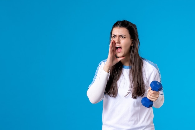 Jovem mulher segurando halteres azuis de frente