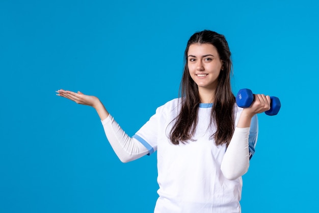 Jovem mulher segurando halteres azuis de frente