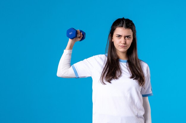 Jovem mulher segurando halteres azuis de frente