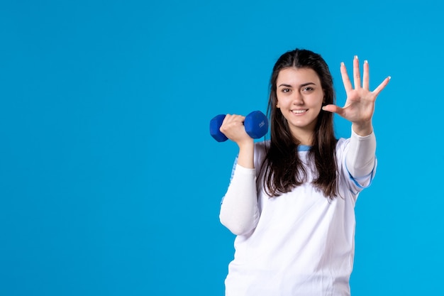 Jovem mulher segurando halteres azuis de frente