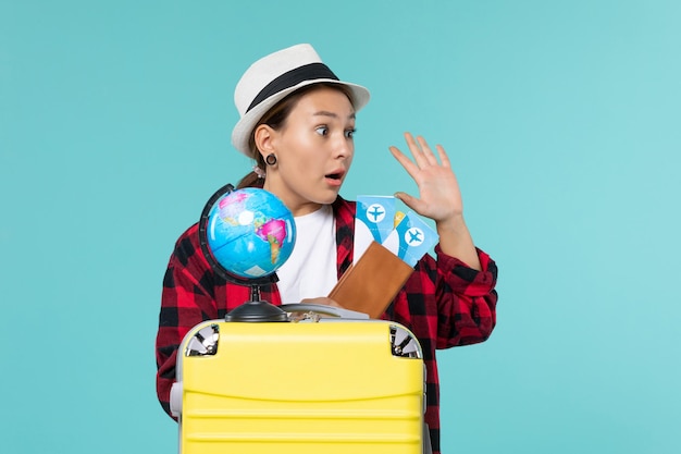 Jovem mulher segurando ingressos de frente para o espaço azul