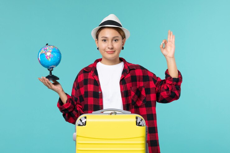 Foto grátis jovem mulher segurando o globo no espaço azul claro de frente