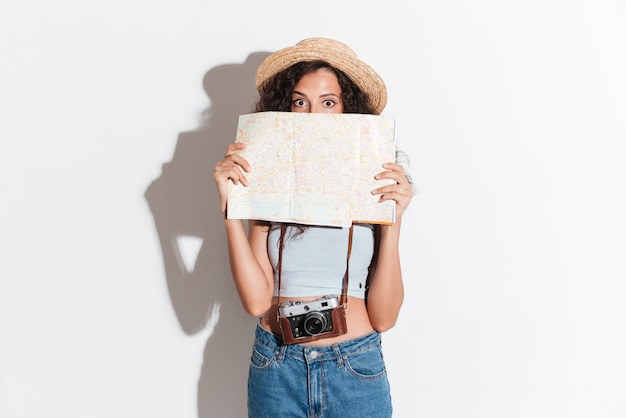 Jovem mulher segurando o mapa e olhando para a câmera isolada