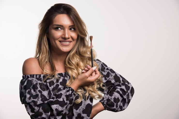 Foto grátis jovem mulher segurando o pincel, olhando em frente na parede branca.