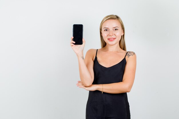 Jovem mulher segurando o smartphone em uma camiseta preta e parecendo alegre