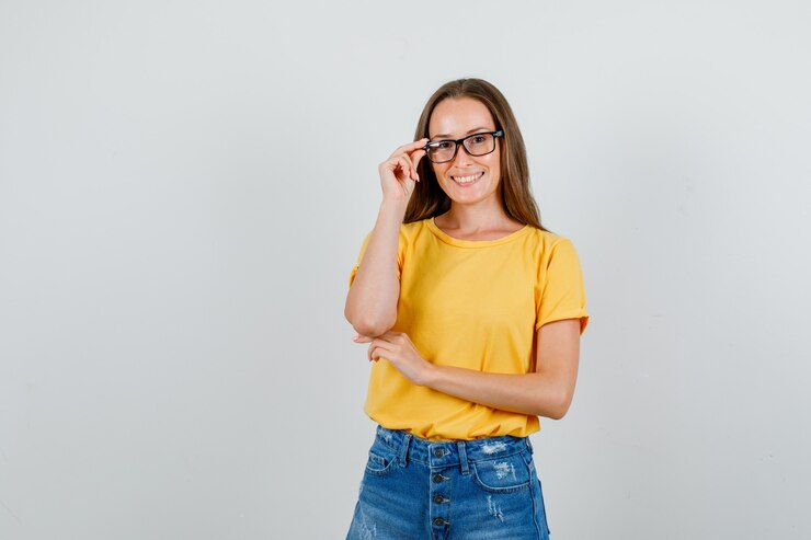 Foto grátis jovem mulher segurando os óculos em uma camiseta, shorts e parecendo alegre