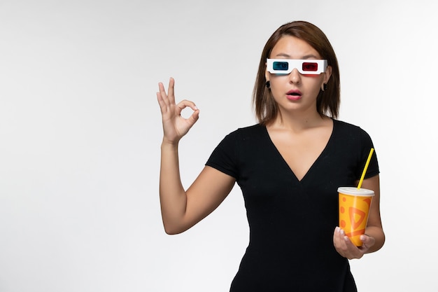 Foto grátis jovem mulher segurando refrigerante em óculos de sol d na superfície branca de vista frontal