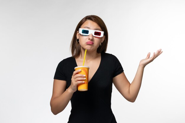 Jovem mulher segurando refrigerante em óculos de sol na superfície branca de vista frontal