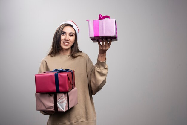 Jovem mulher segurando três caixas de presentes de Natal.