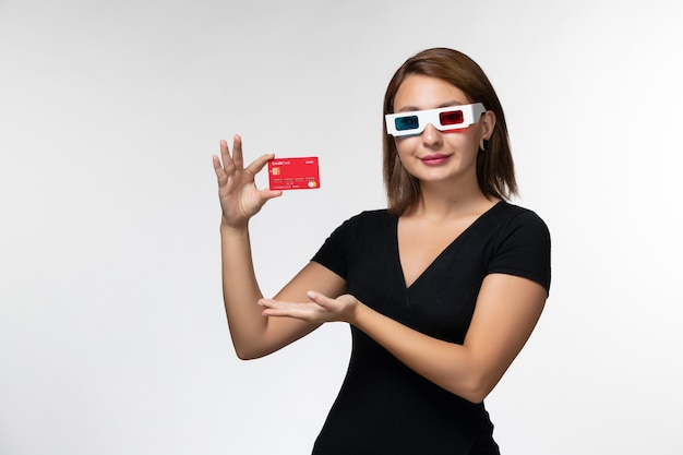 Jovem mulher segurando um cartão do banco em óculos de sol -d sorrindo na superfície branca de frente