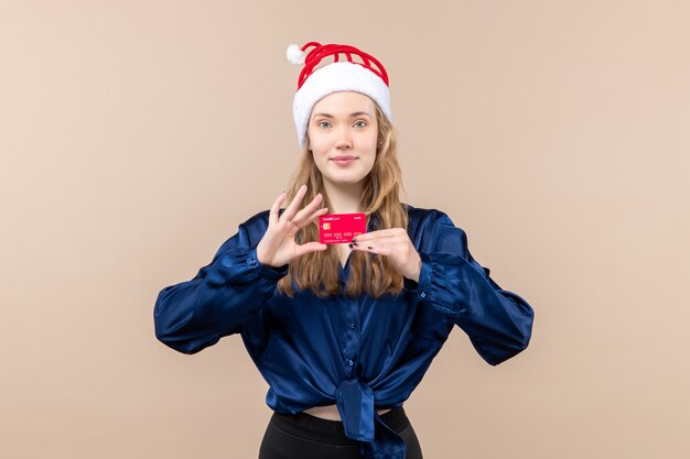 Jovem mulher segurando um cartão vermelho no fundo rosa foto de férias ano novo emoção Natal dinheiro