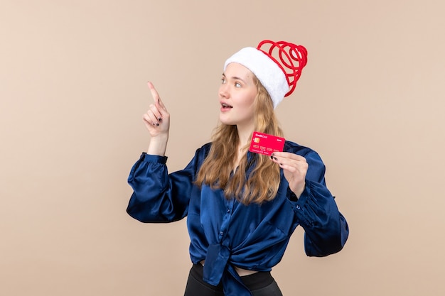 Jovem mulher segurando um cartão vermelho no fundo rosa, foto de férias, ano novo, Natal, dinheiro, emoções