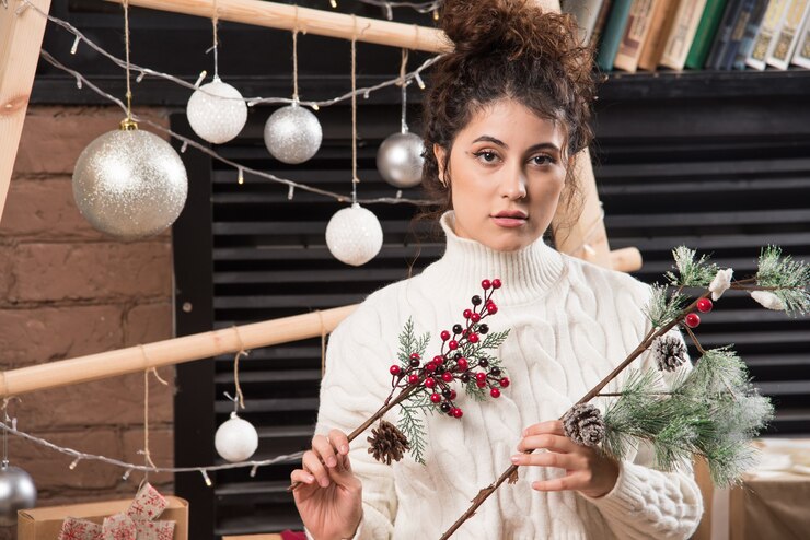 Foto grátis jovem mulher segurando um galho de baga de azevinho de natal