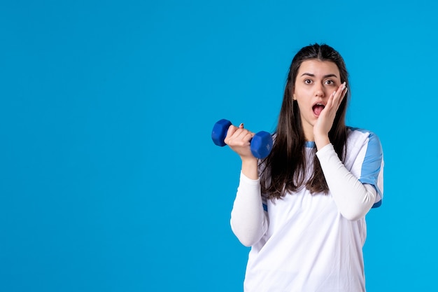 Jovem mulher segurando um haltere azul de frente