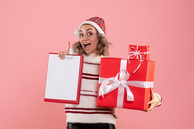 Jovem mulher segurando um presente de natal e uma nota frontal