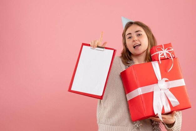 Jovem mulher segurando um presente de natal e uma nota frontal