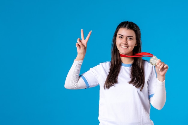 Jovem mulher segurando uma bola de futebol na parede azul de frente