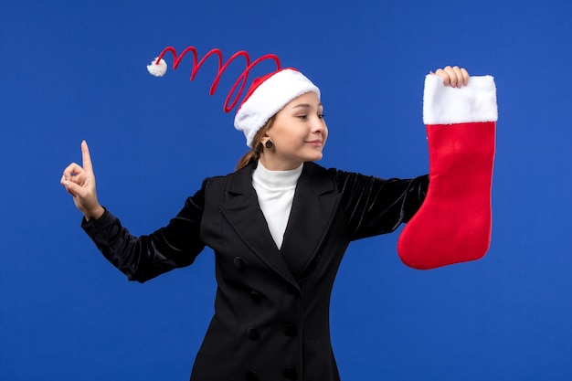 Jovem mulher segurando uma meia vermelha de natal na mesa azul, de frente para o feriado humano, ano novo