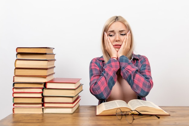 Jovem mulher sentada com livros e lendo em branco