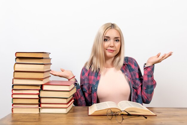 Jovem mulher sentada com livros e lendo em branco