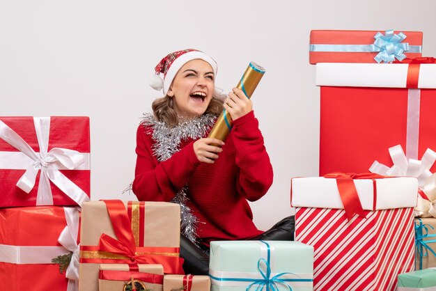 Jovem mulher sentada de frente para os presentes de Natal