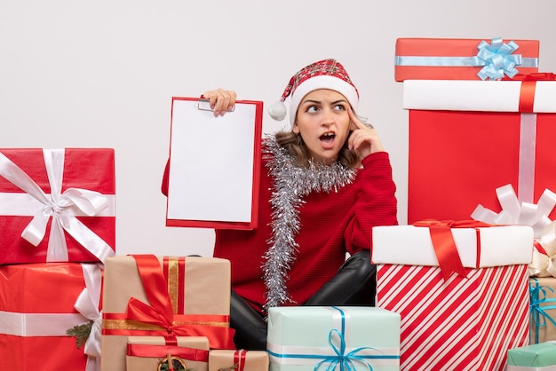 Jovem mulher sentada de frente para os presentes de Natal