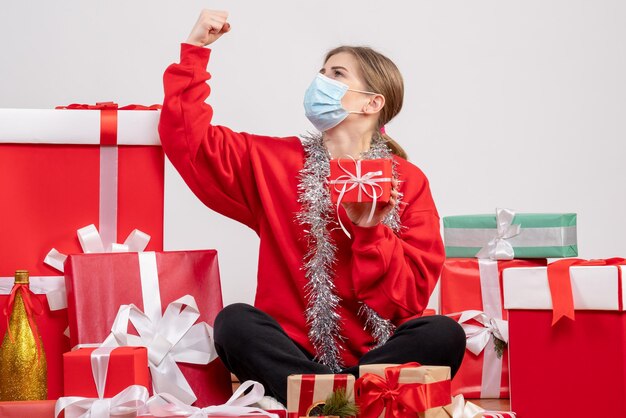 Jovem mulher sentada de frente para os presentes de Natal