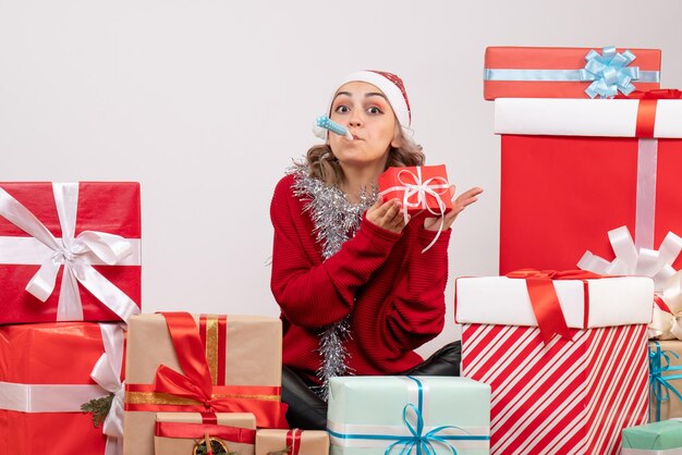 Jovem mulher sentada de frente para os presentes de Natal