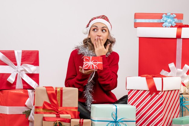 Jovem mulher sentada de frente para os presentes de Natal