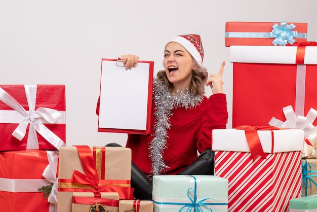 Jovem mulher sentada de frente para os presentes de natal